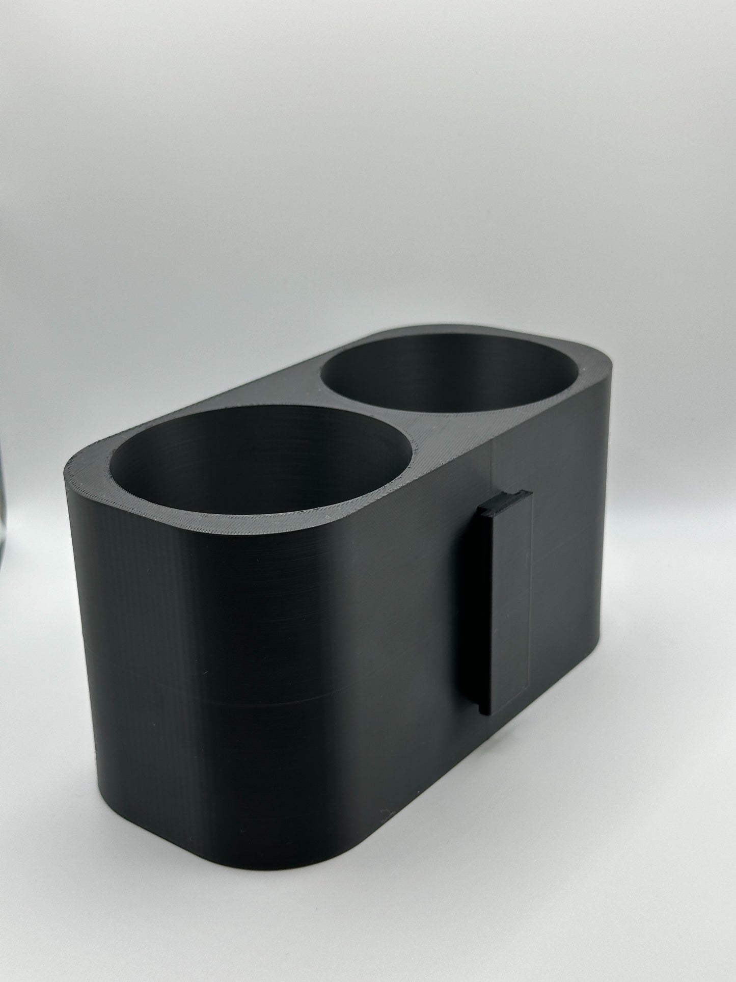 Zijaanzicht van een 3D-geprinte dubbele bekerhouder met een matzwarte afwerking.